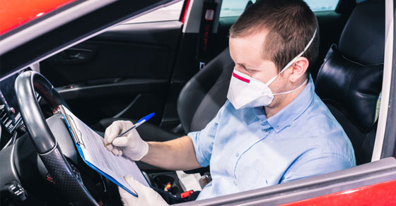 Contractor wearing a mask filling out form in his car